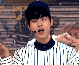 a young man wearing a baseball cap and striped shirt is singing into a microphone ..