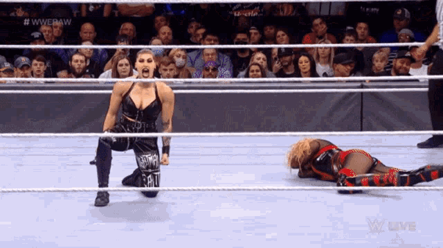 a female wrestler is kneeling down next to another wrestler laying on the ground