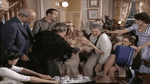 a group of people are gathered in a living room and one woman is holding a blue bag