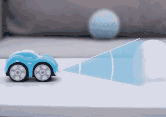 a blue toy car is driving past a white ball on a table