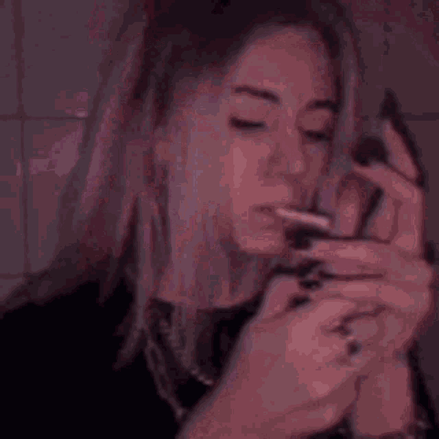 a woman is lighting a cigarette in the dark .