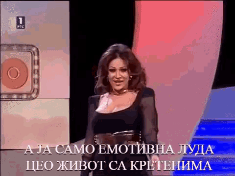 a woman in a black dress is standing in front of a sign that says a ja samo emotivna lyda