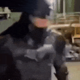 a man in a mask is standing in a room with a gun .