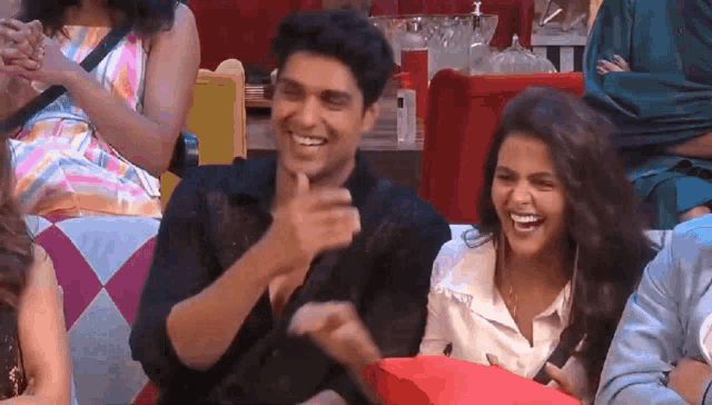 a man and a woman are sitting next to each other on a couch and smiling .