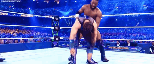 two wrestlers are wrestling in a wrestling ring with a crowd watching .