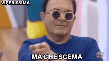 a man wearing sunglasses and a blue shirt is pointing at the camera and says ma che scena .
