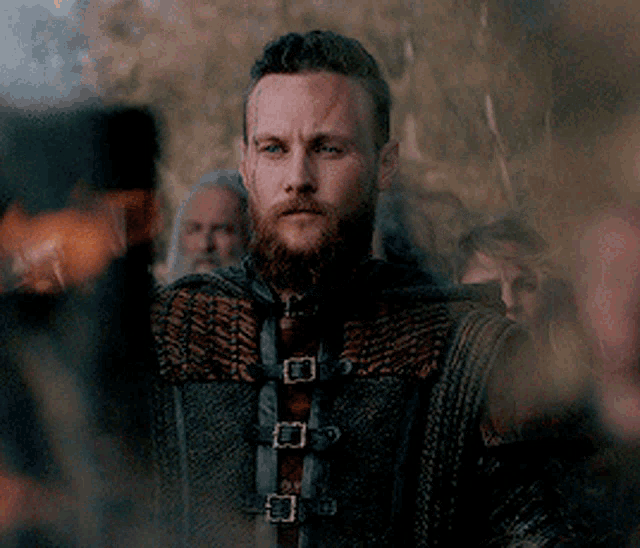 a man with a beard is wearing a leather jacket with buckles