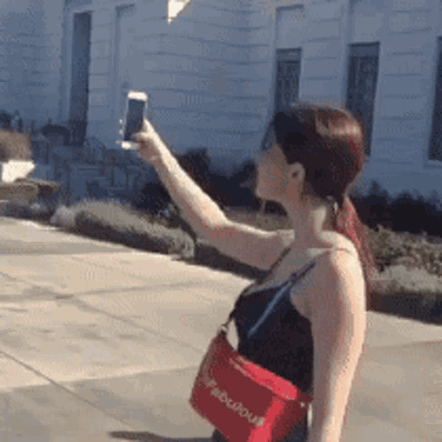 a woman taking a picture of herself with a cell phone
