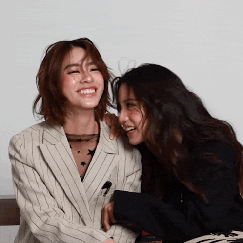a woman in a striped jacket is laughing next to another woman in a black jacket