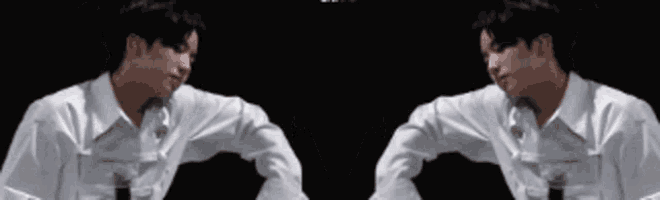 two men in white shirts are shaking hands in a dark room
