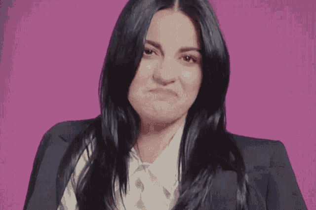 a woman with long black hair is wearing a suit jacket and a white shirt
