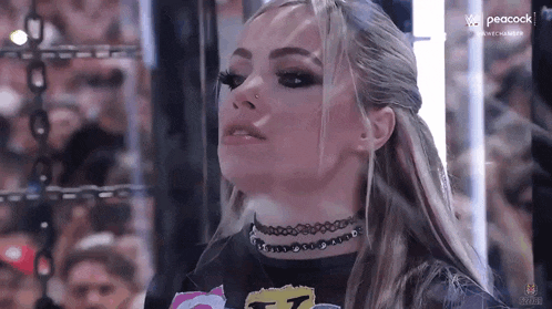 a woman wearing a choker and a black shirt is standing in a boxing ring .