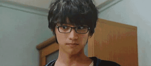 a young man wearing glasses is making a funny face and looking at the camera .