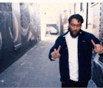 a man with a beard is giving the middle finger in an alley