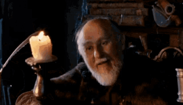a man with a beard is laying down in front of a candle
