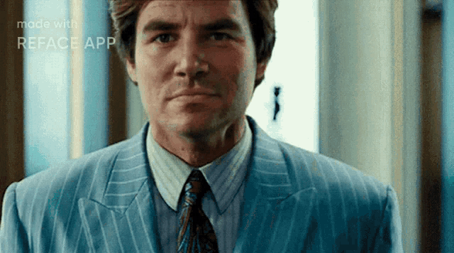 a man in a suit and tie is looking at the camera .