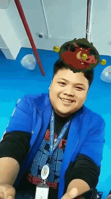 a man wearing a blue jacket with a lanyard around his neck has a picture of a cartoon character on his head