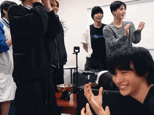 a group of young men are standing around a table and one of them is wearing a t-shirt that says supreme