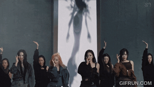 a group of women are dancing in front of a wall that says gifrun.com on it