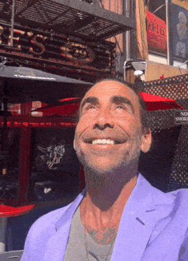 a man in a purple jacket is smiling in front of a restaurant that says corona