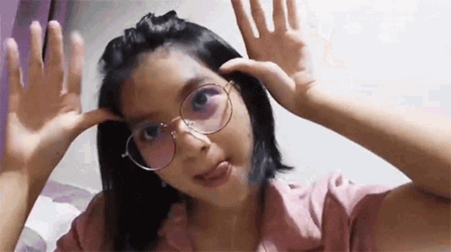 a young girl wearing glasses is making a funny face and sticking out her tongue .