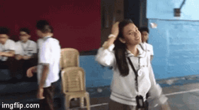 a girl with a lanyard around her neck is standing in front of a group of children .