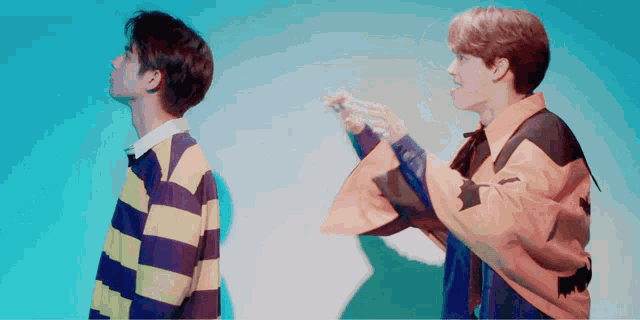 two young men are standing next to each other and one of them is wearing a yellow jacket