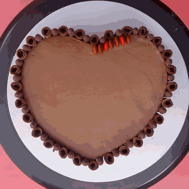 a chocolate cake in the shape of a heart is surrounded by chocolate balls