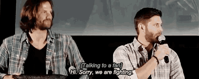 two men are talking to each other while holding microphones .