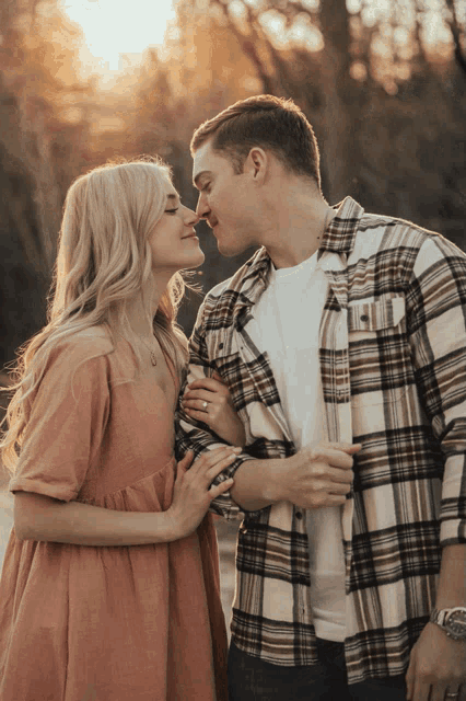 a man and a woman are kissing and the woman is wearing a plaid shirt