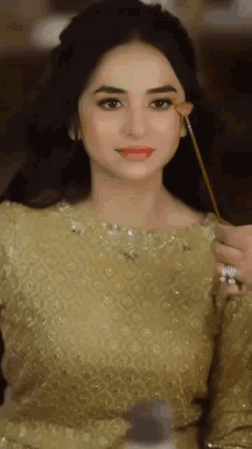 a woman in a gold dress is getting her makeup applied