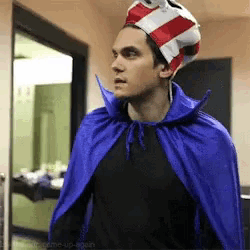 a man wearing a blue cape and a red white and blue striped hat