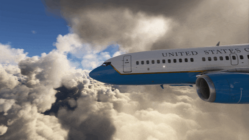 a blue and white united states airplane flies through the clouds
