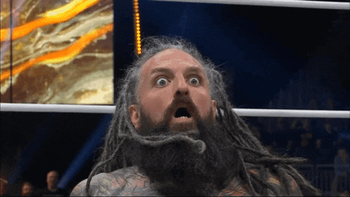 a man with dreadlocks and a beard stands in a ring with his mouth open