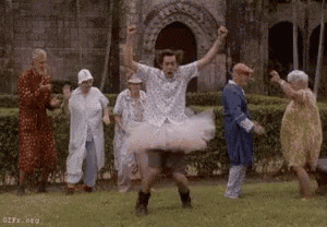 a man in a tutu is jumping in the air in front of a group of people .