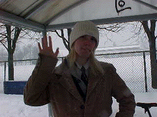 a woman wearing a hat and a coat is standing in the snow giving the peace sign