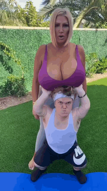 a woman with very large breasts is holding a smaller man on her shoulders .