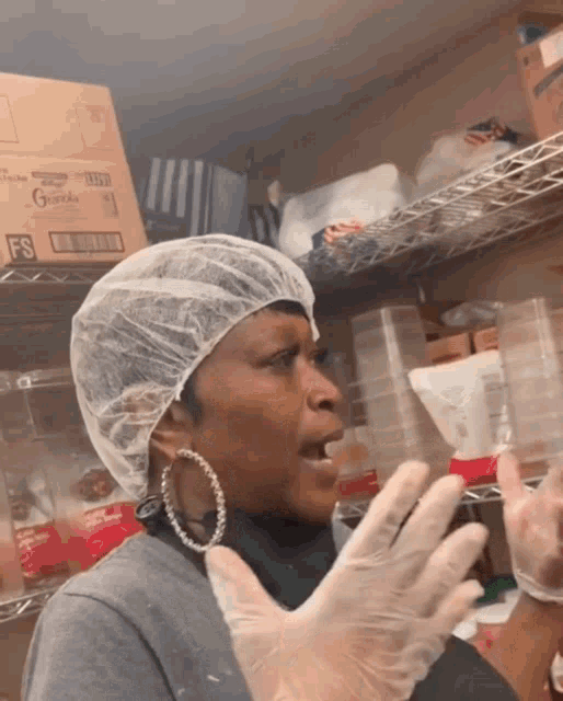 a woman wearing a plastic cap and gloves stands in front of a box of guardian
