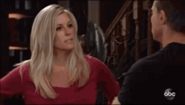 a woman in a red shirt is talking to a man in a black shirt in a room .