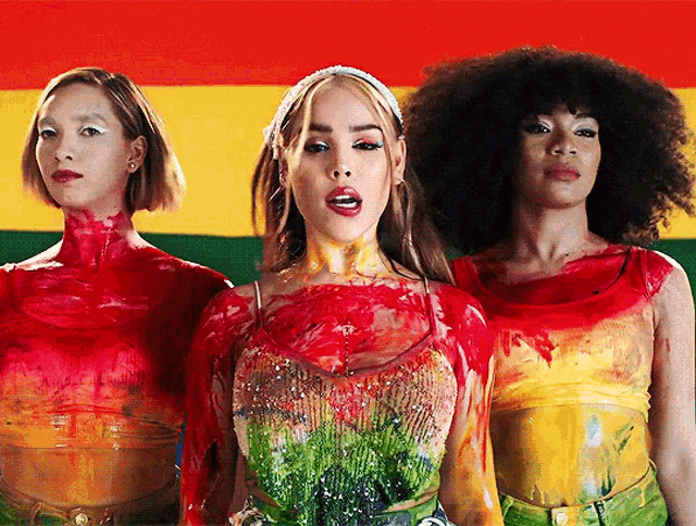 three women are standing in front of a colorful background