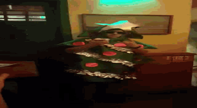 a man in a christmas tree costume is standing in a dark room
