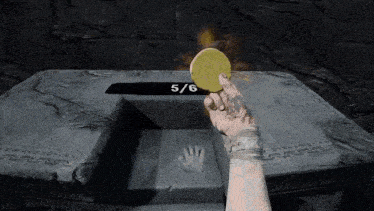 a person is holding a coin in front of a stone plaque with the number 5/6 on it