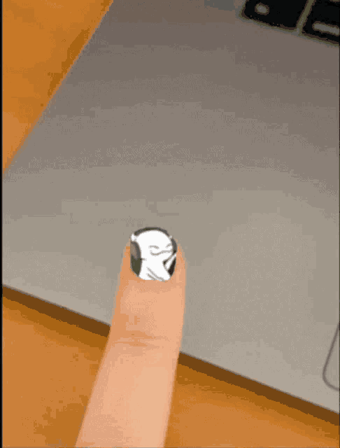 a close up of a person 's thumb with a sticker on it in front of a laptop