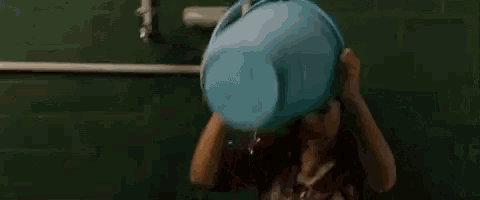 a woman is holding a blue bucket over her head .