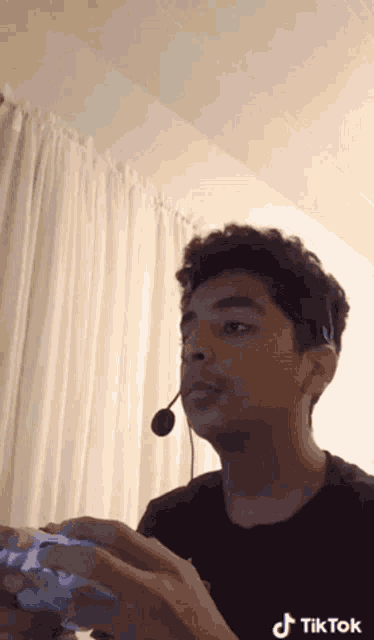 a man wearing a headset is playing a video game with a controller .