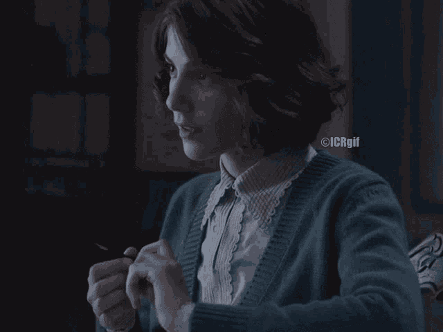 a woman wearing a blue sweater is sitting at a table