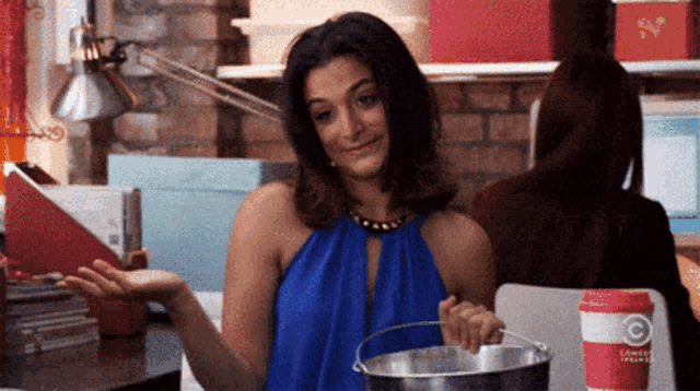 a woman in a blue dress is holding a bucket in front of a cup that says comedy central