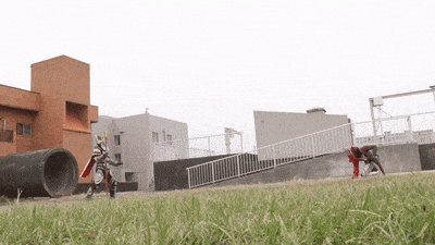 two action figures are fighting in a grassy field near a building