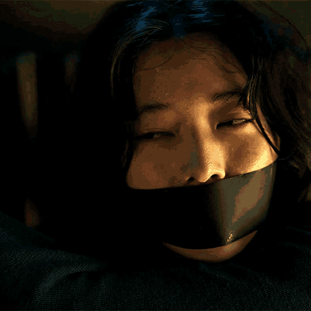 a close up of a woman 's face with a black tape around her mouth