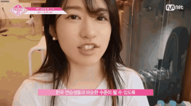 a woman is sitting in front of a sign that says mnet on it